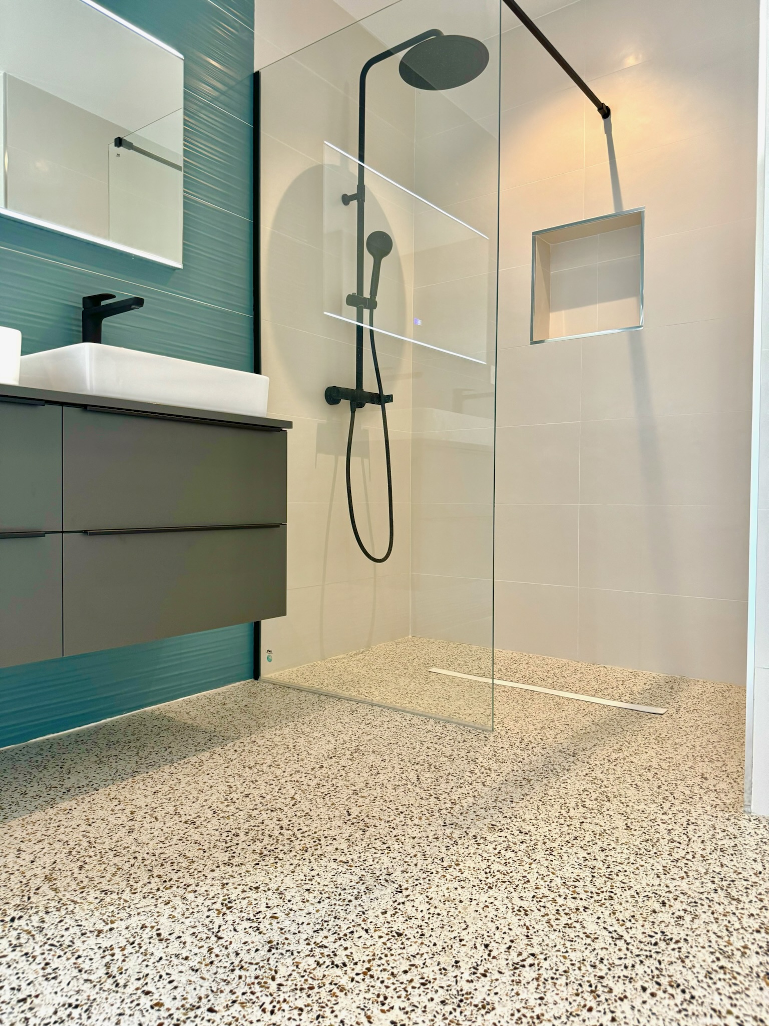 Terrazo continuo crema en baño con ducha a ras de suelo