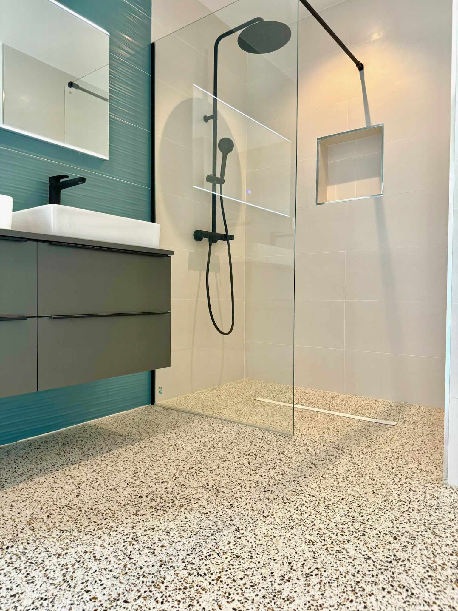 Baño con pavimento Stone Feel, ducha de obra y azulejo espiga azul turquesa