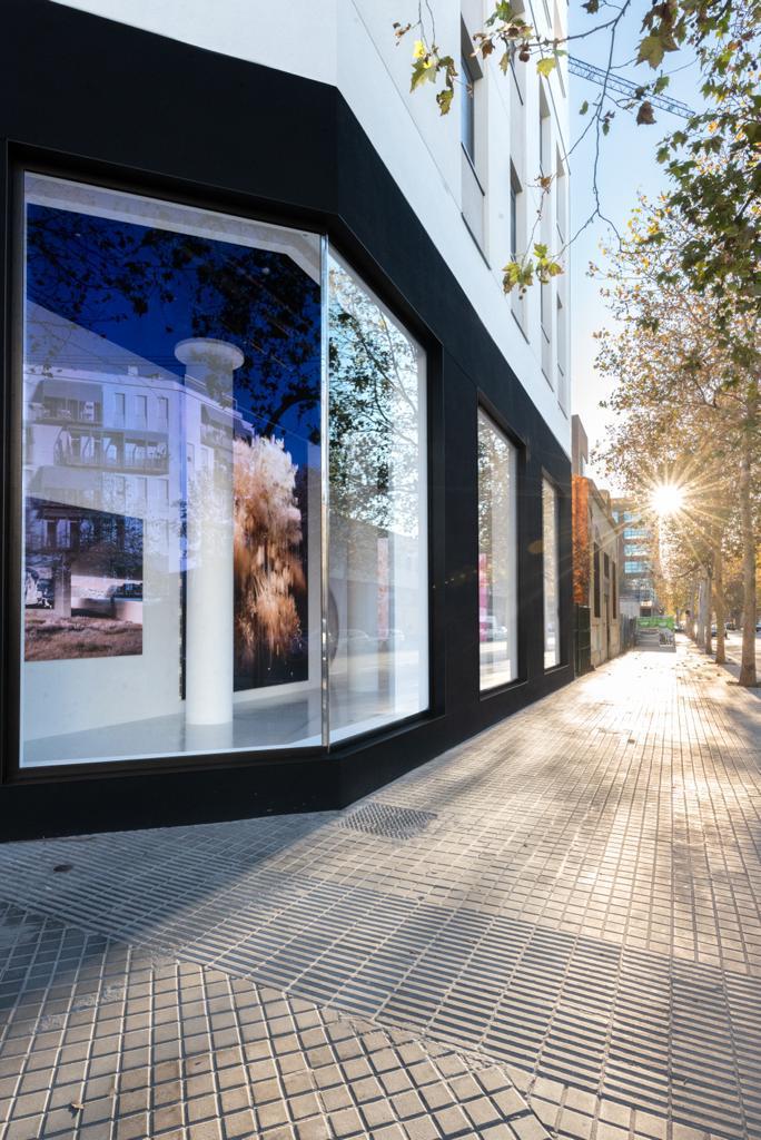 Fachada exterior galería DecopoX con sol de invierno y pavimento continuo visible